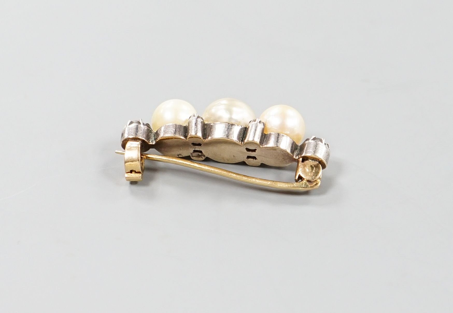A yellow metal, three stone cultured pearl and six stone diamond brooch, 34mm, gross weight 8.1 grams.